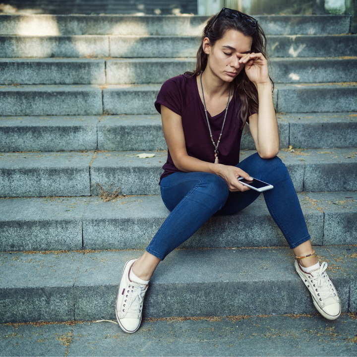 Woman sitting on steps feeling stressed and overwhelmed, representing anxiety and mental health