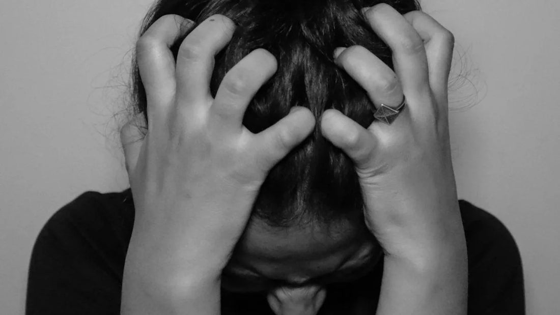 Person holding head in hands showing signs of stress and anxiety. 