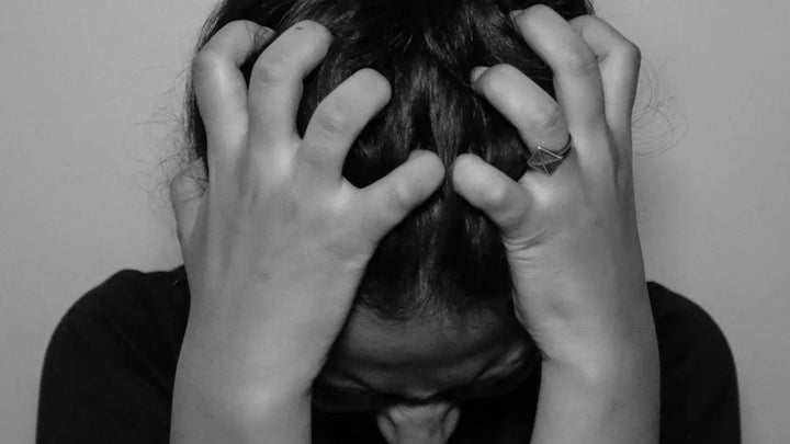 Person holding head in hands showing signs of stress and anxiety. 