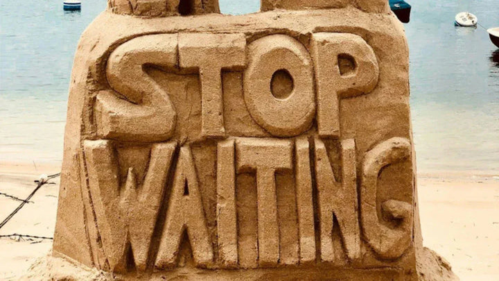 Sand sculpture that says STOP WAITING on a beach, representing taking action during watch and wait. 